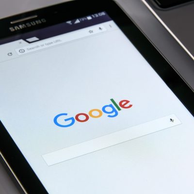 彩经网基本走势图编辑部内容负责人在办公桌前核对走势表格，屏幕上是深绿色数据界面，桌面摊开着标注过的纸质记录